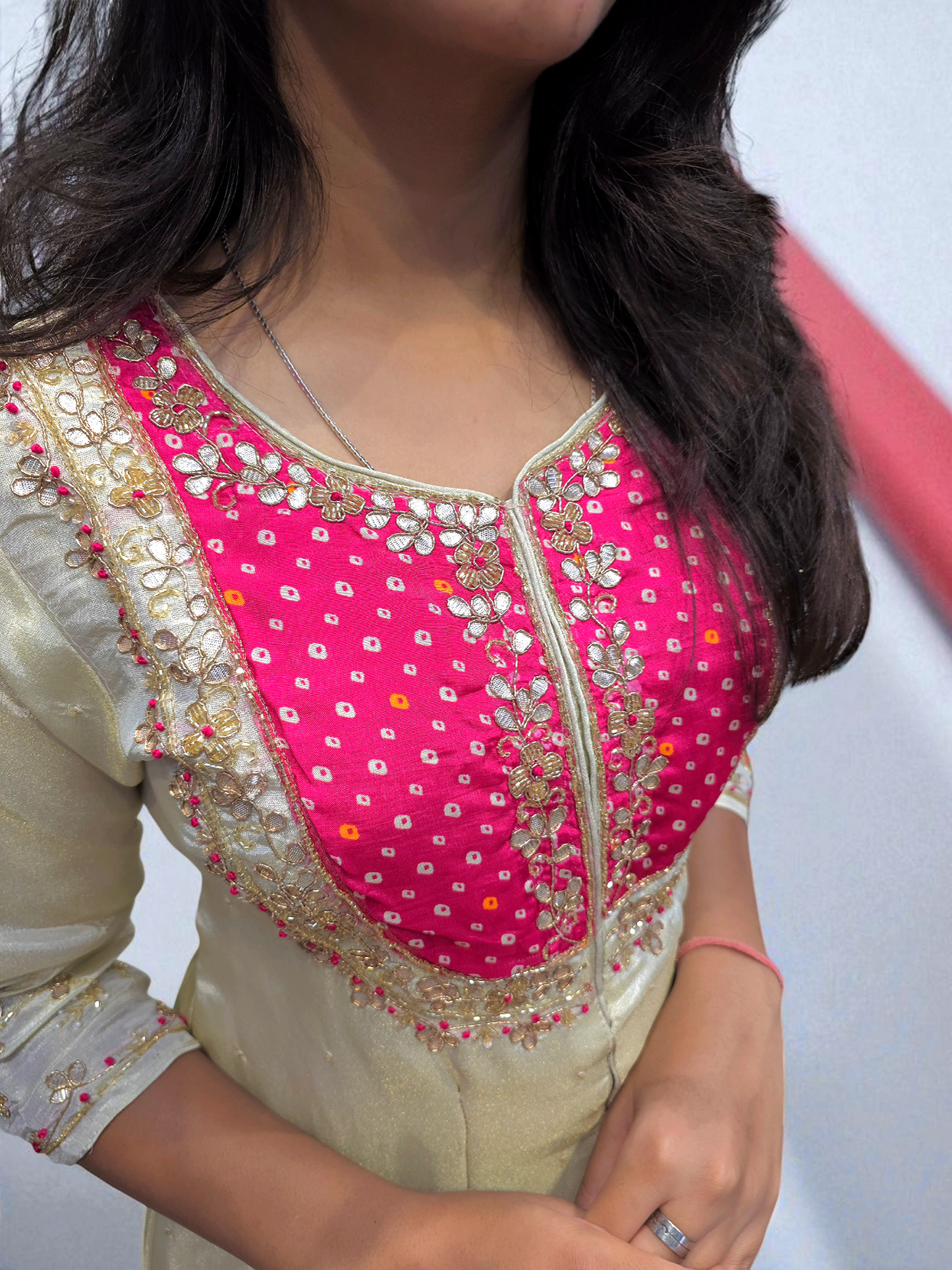 Close-up of a person wearing a pink and gold embroidered blouse with a blurred background