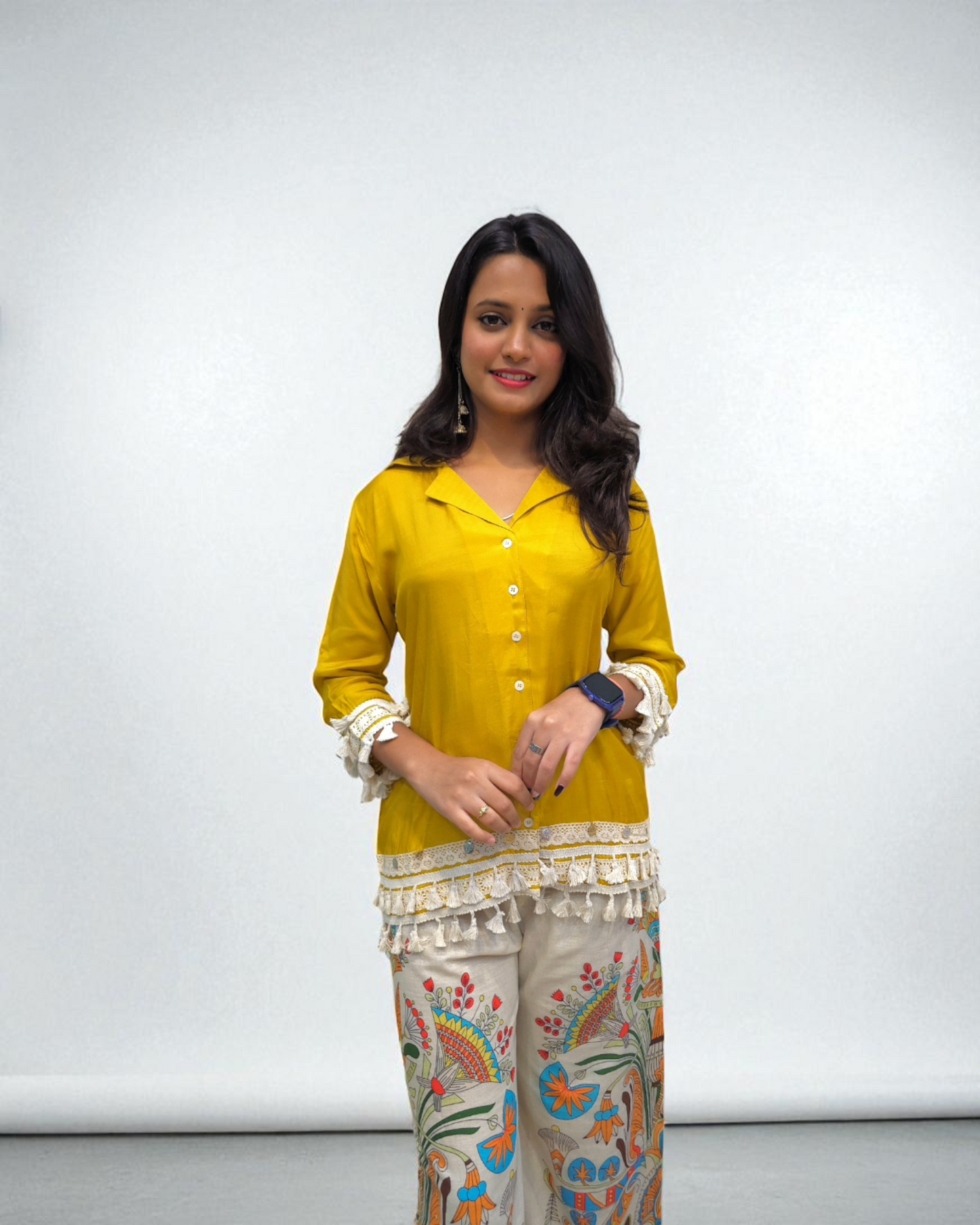 Woman wearing a yellow top and patterned pants against a white background