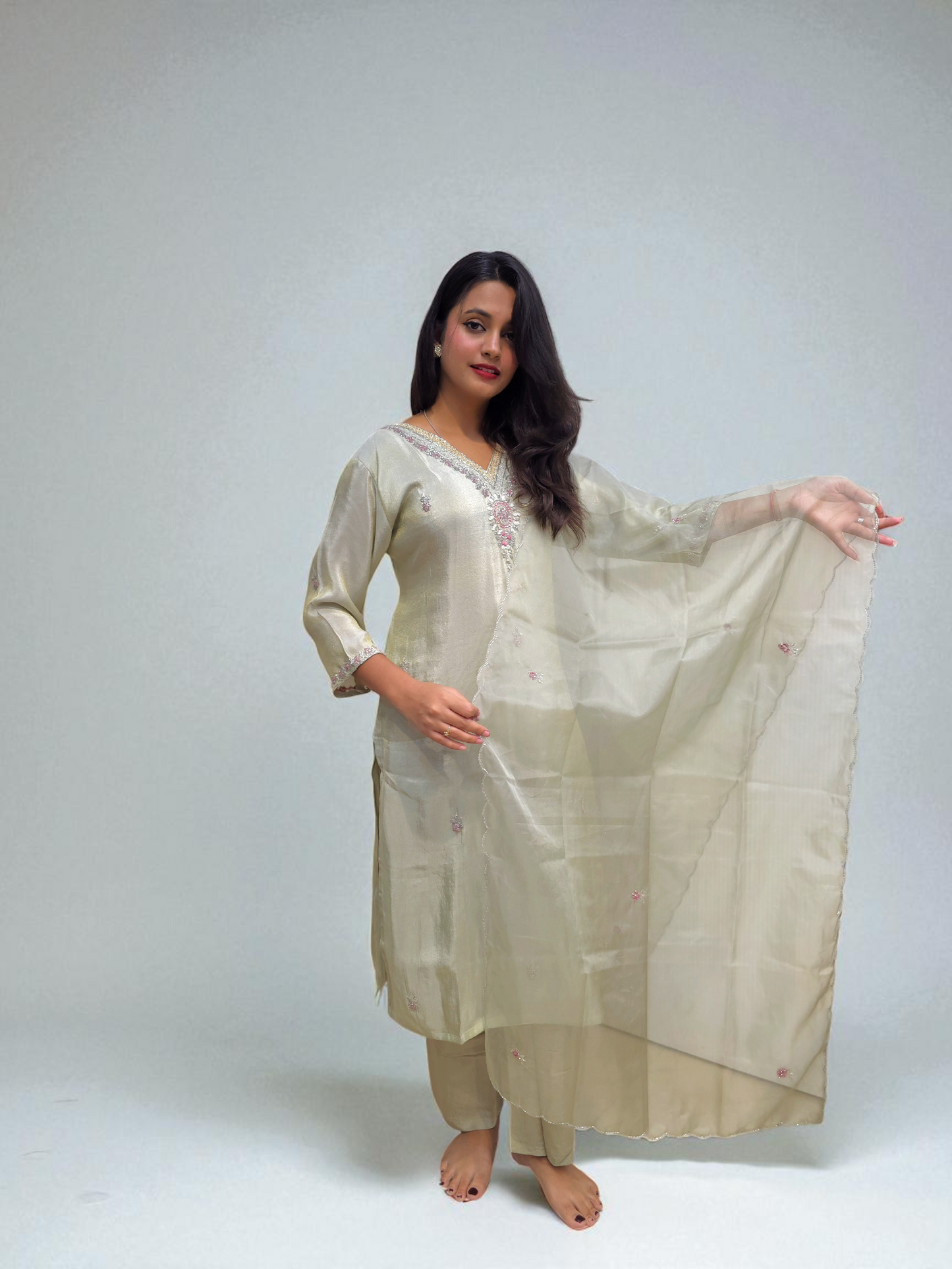 Elegant woman wearing a ivory pure shimmer tissue kurta set with handwork, showcasing traditional style for special occasions.
