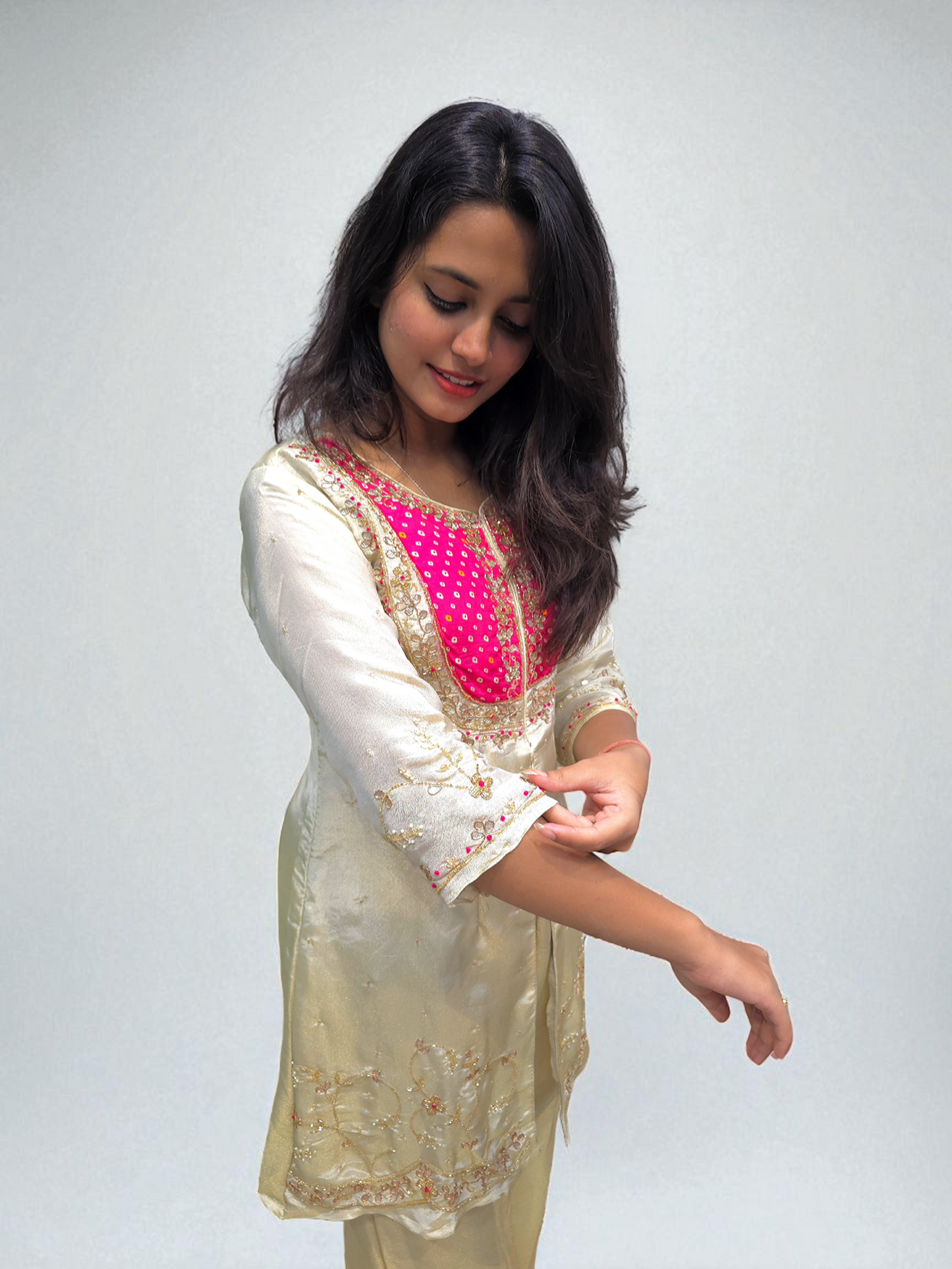 Woman wearing a traditional outfit with a white and pink top on a plain background
