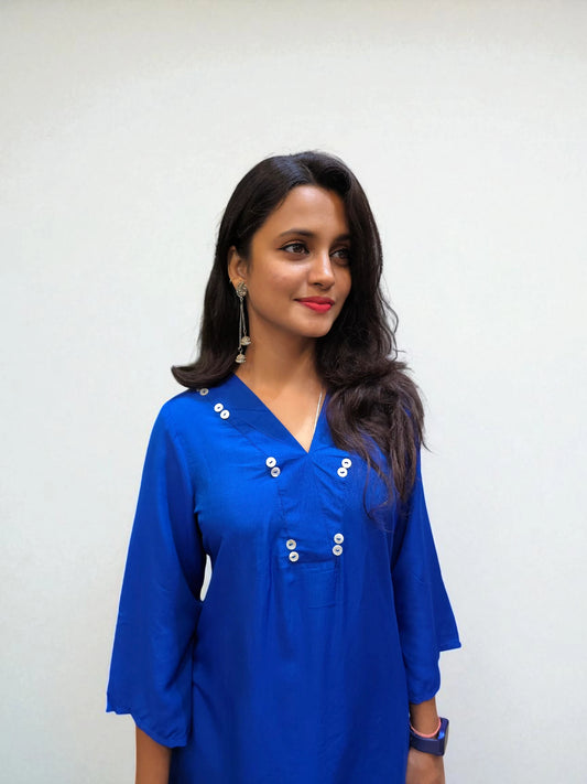 Woman wearing a royal blue asymmetrical kurti with button detailing from Ambika Boutique.