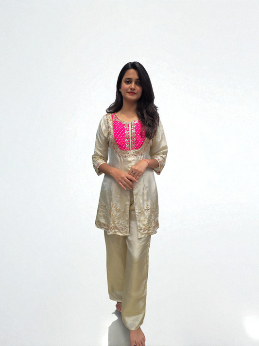 Woman wearing a beige kurta with pink embroidery on a white background
