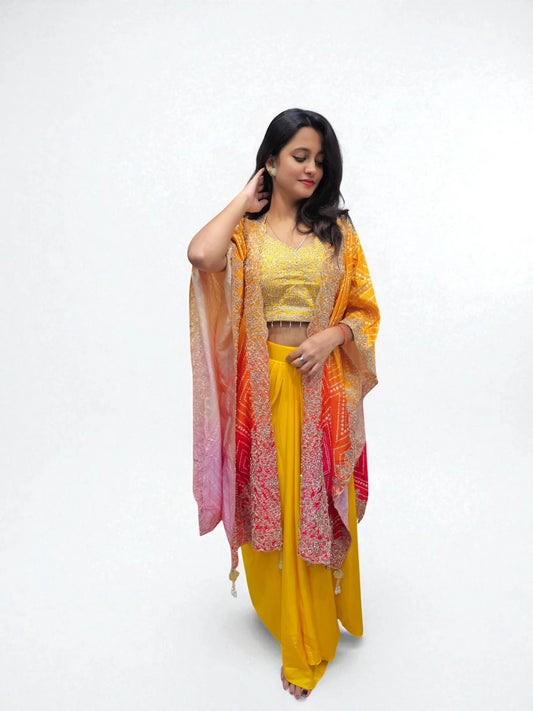Woman wearing designer yellow embroidered dhoti set with sequin blouse and orange-pink bandhani Cape