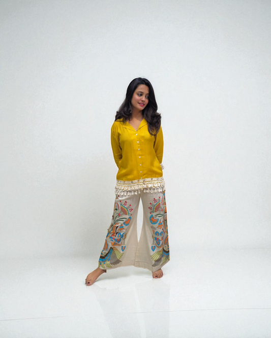 Woman wearing a yellow top and patterned pants on a white background