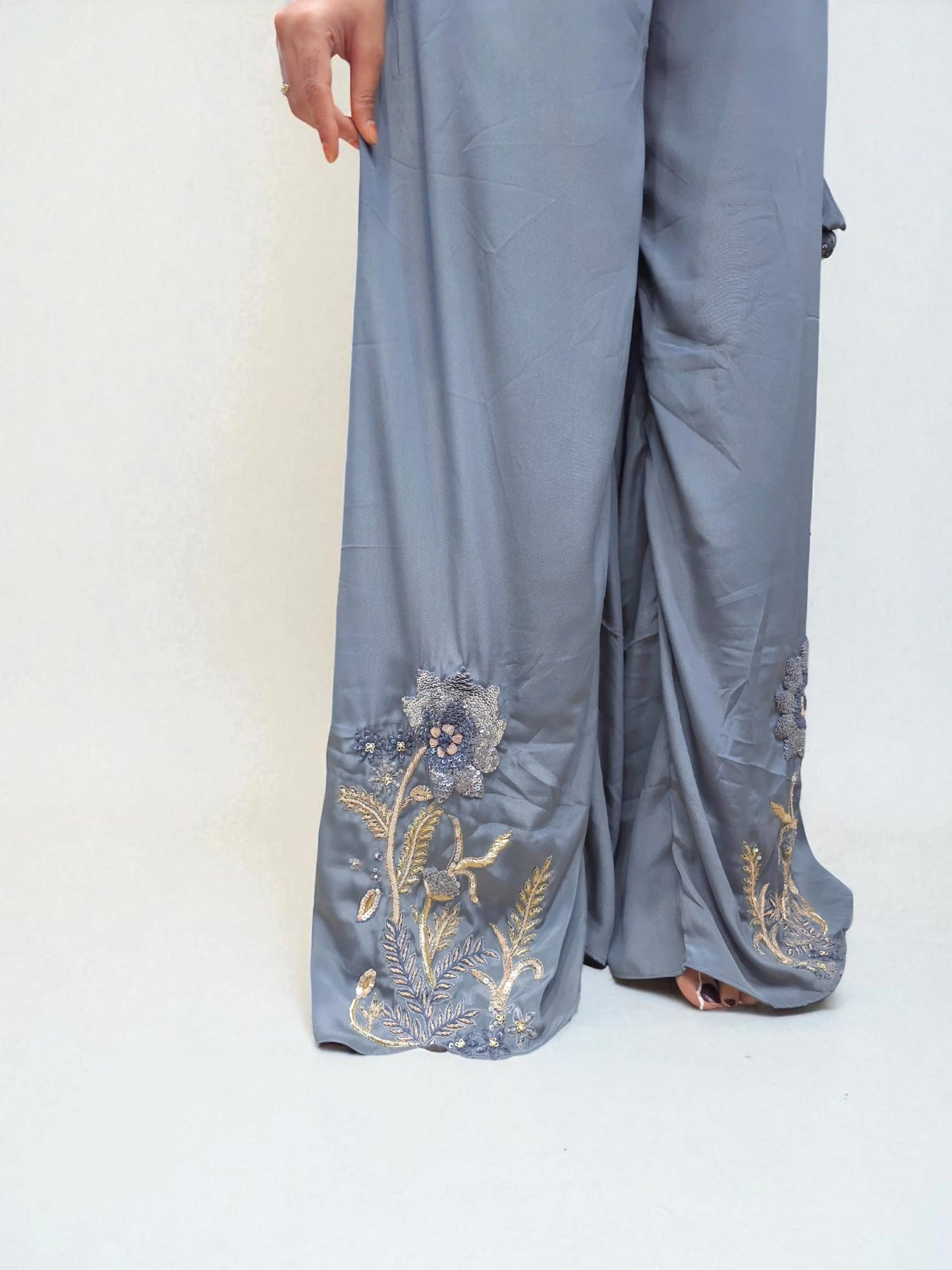 Light blue pants with floral embroidery on a white background