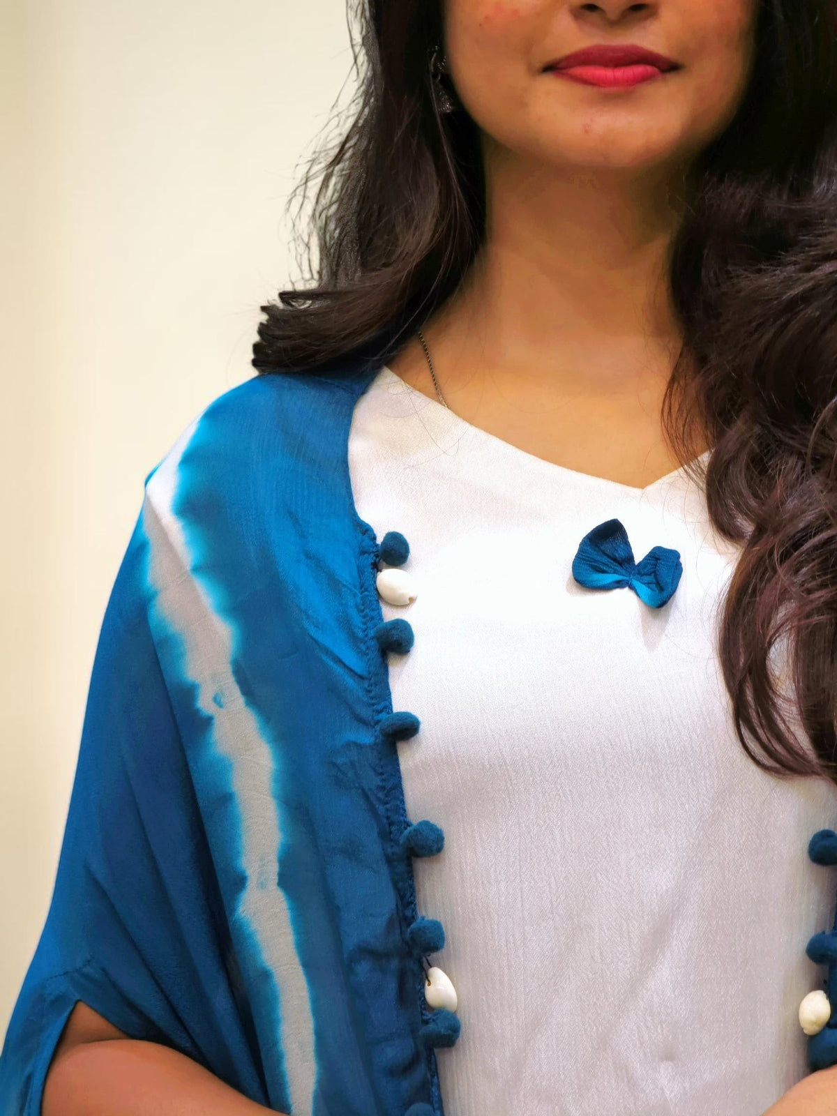Woman wearing a blue and white outfit with a blue bow detail on a beige background
