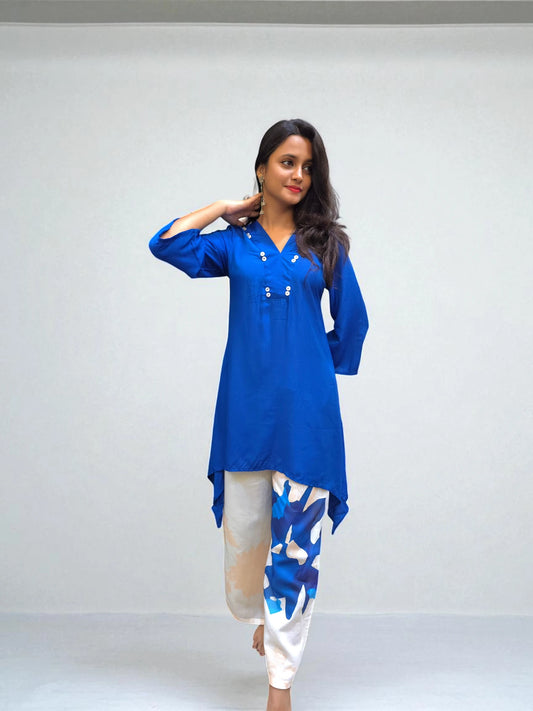 Blue asymmetrical kurti styled with white printed pants in a chic Indo-Western look.