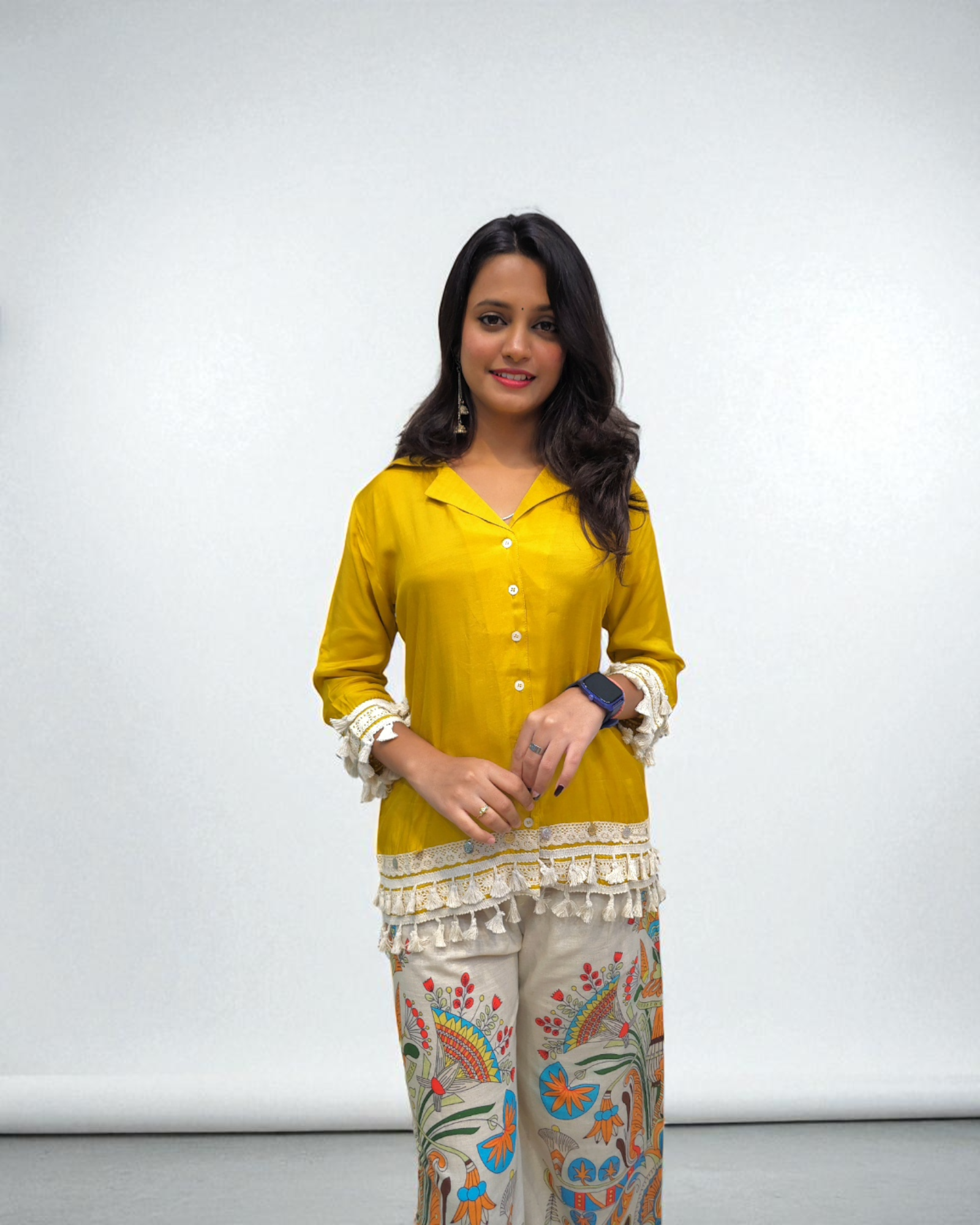 Woman wearing a yellow top and patterned pants against a white background